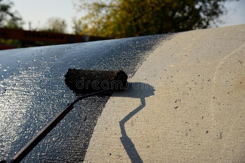 travailleur-de-roofer-peignant-le-goudron-ou-bitume-houille-noir-127924988